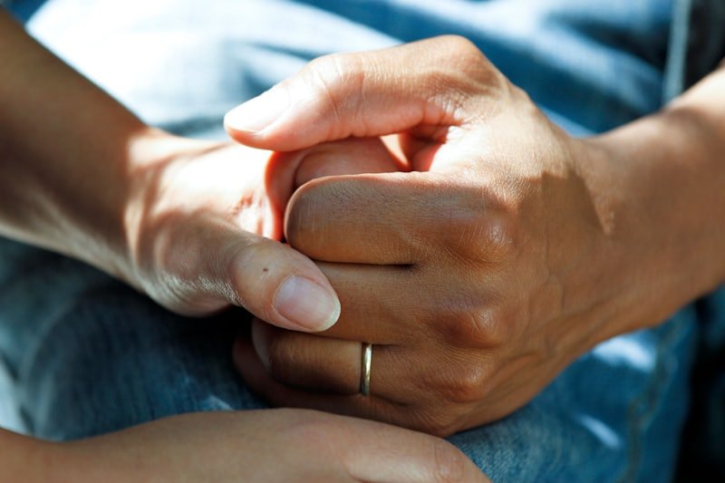 Two people holding hands, one reassuring the other